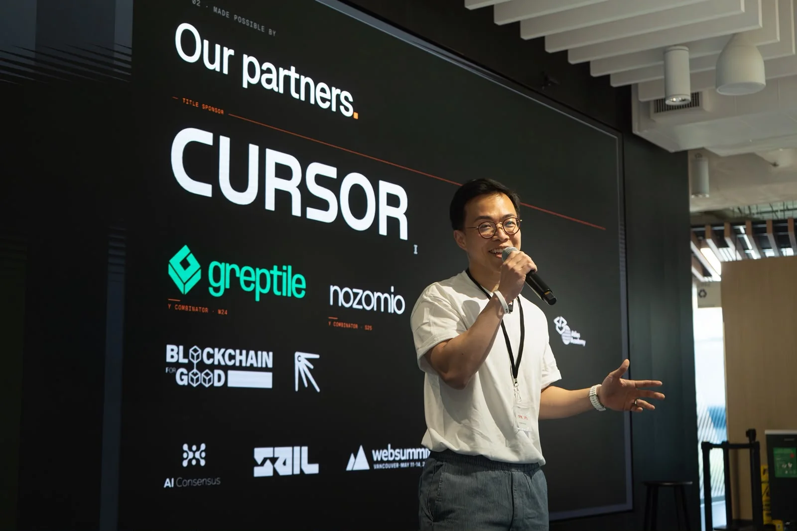 Young Guns alumnus speaking with a microphone at a tech startup event, partner logos projected behind him