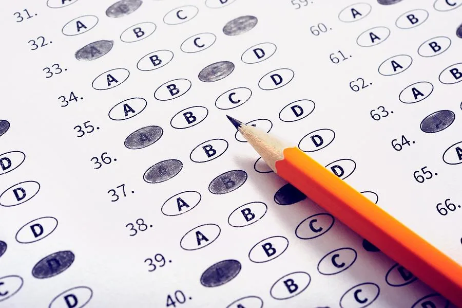 Orange pencil resting on a filled-in multiple-choice exam answer sheet