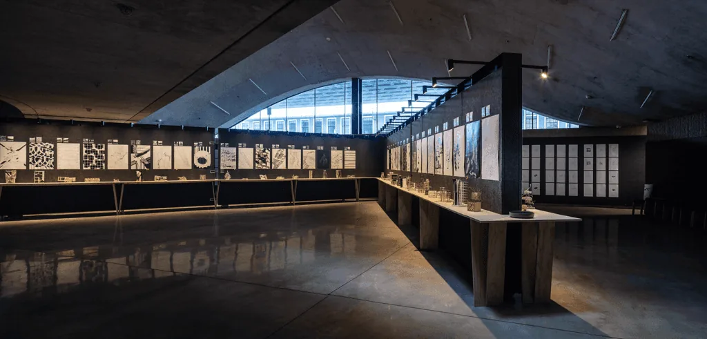 Dimly lit gallery interior with framed artworks and illuminated display cases along a long wall