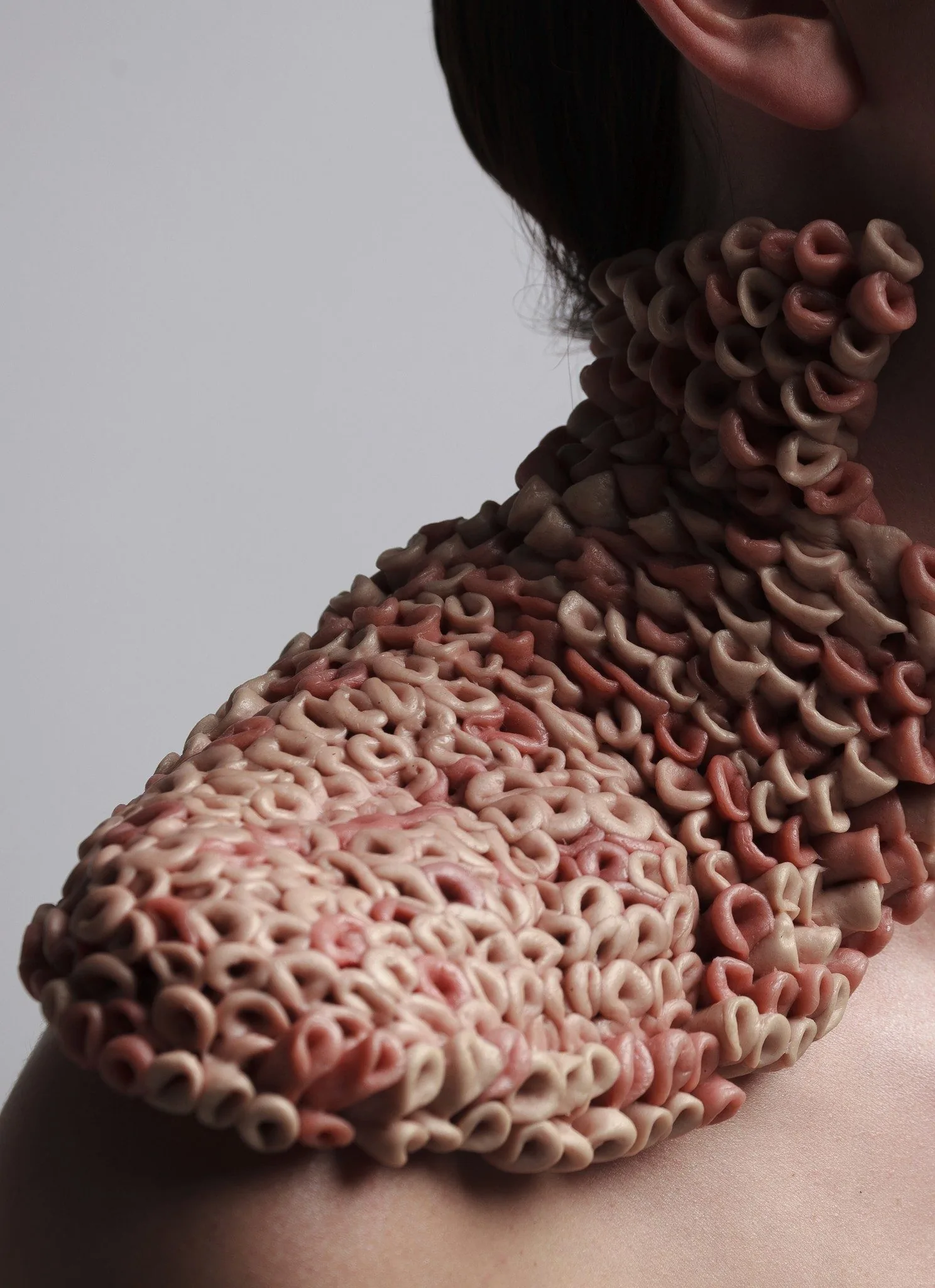 Student fashion piece: sculptural collar of looped flesh-toned forms covering a model's neck and shoulder